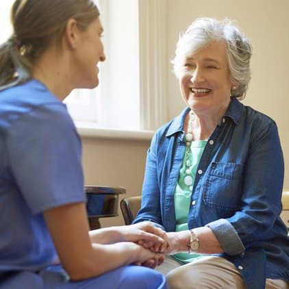 nurse holding elderly woman's hand